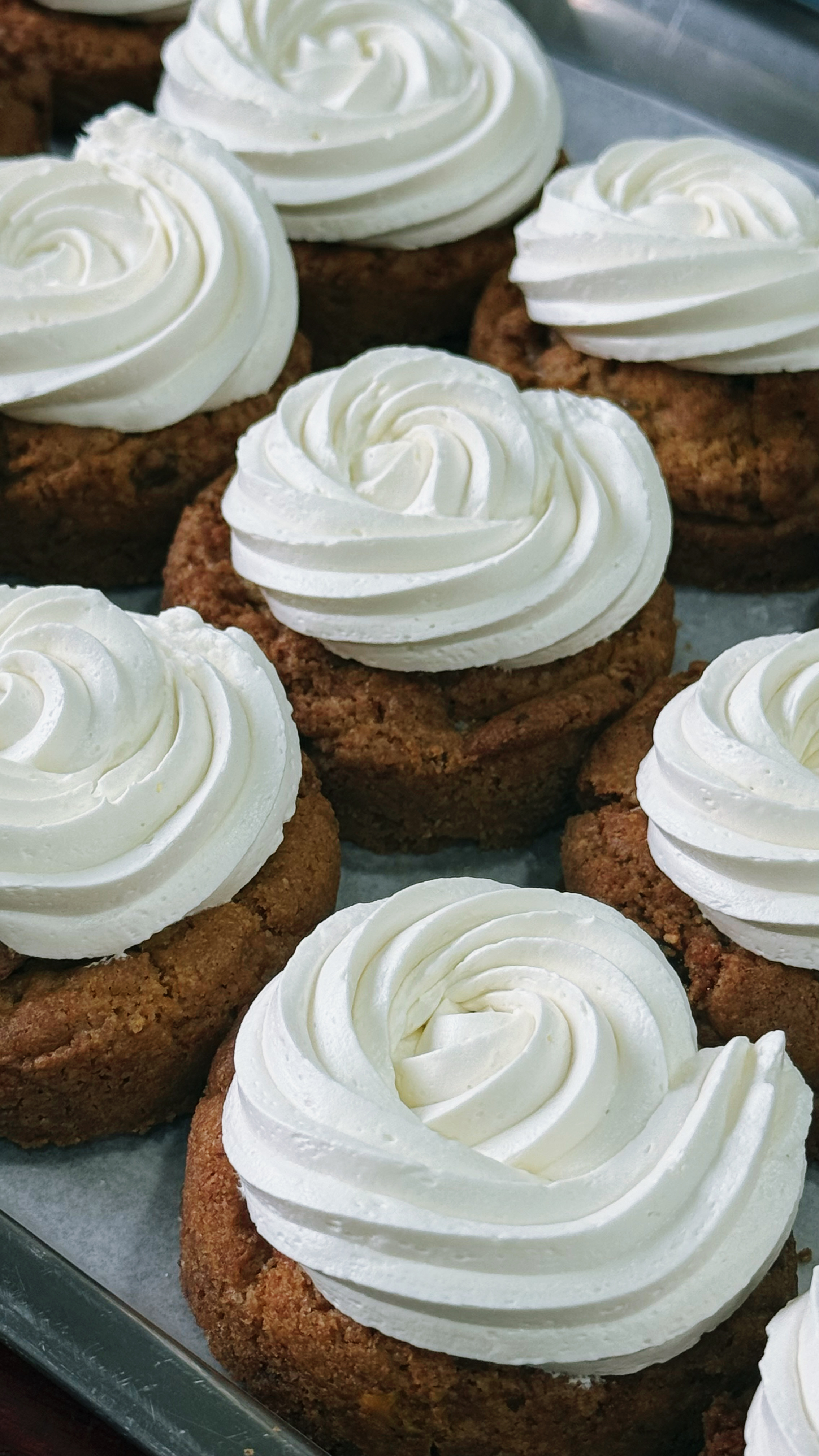 Rows of CUKI cookies topped with white frosting swirls